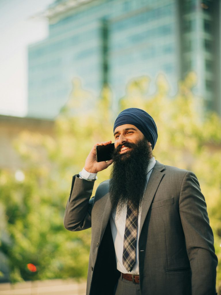 Confident Sikh businessman in formalwear talking on smartphone outside.