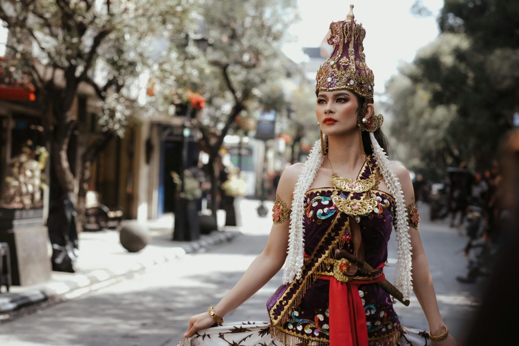 A woman in traditional Indonesian attire walking down a city street.